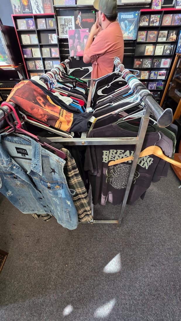 A customer browsing a rack of vintage band tees and denim vests.