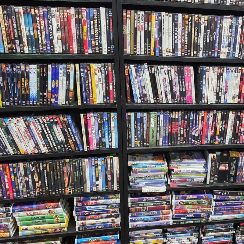 A floor-to-ceiling wall of DVD and VHS shelving packed with titles.