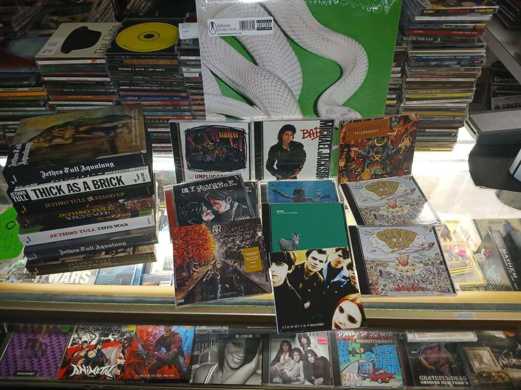 A new-arrivals display on the glass counter with sealed LPs and CDs standing on stands.