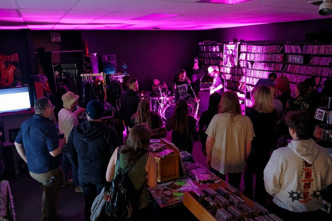 A packed in-store crowd watching a band perform under magenta stage light.